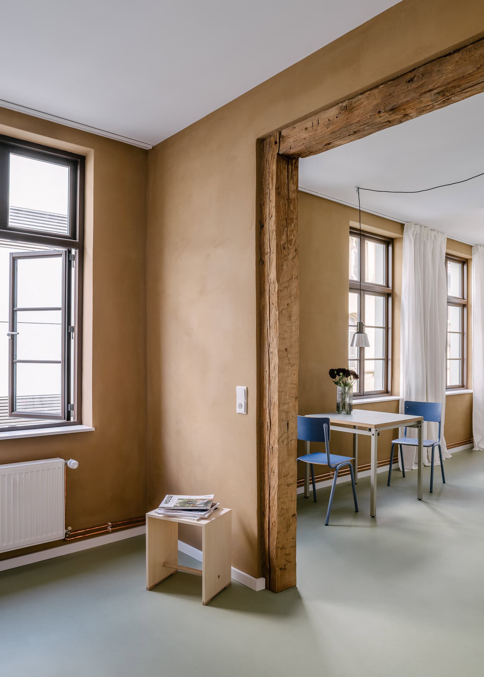 Gemütlicher Raum mit großen Fenstern und Holzbalken 